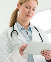 Image of a female Doctor-in-white-coat with- stethoscope typing on an ipad